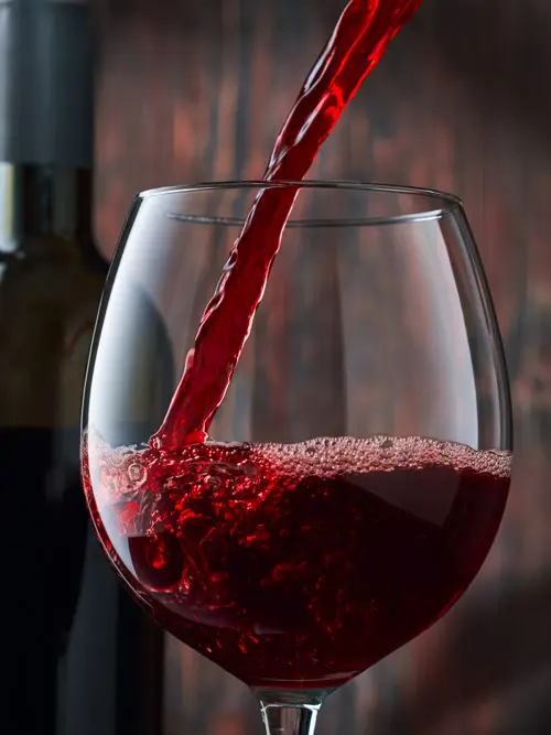 Rotwein wird ins Glas eingeschenkt
